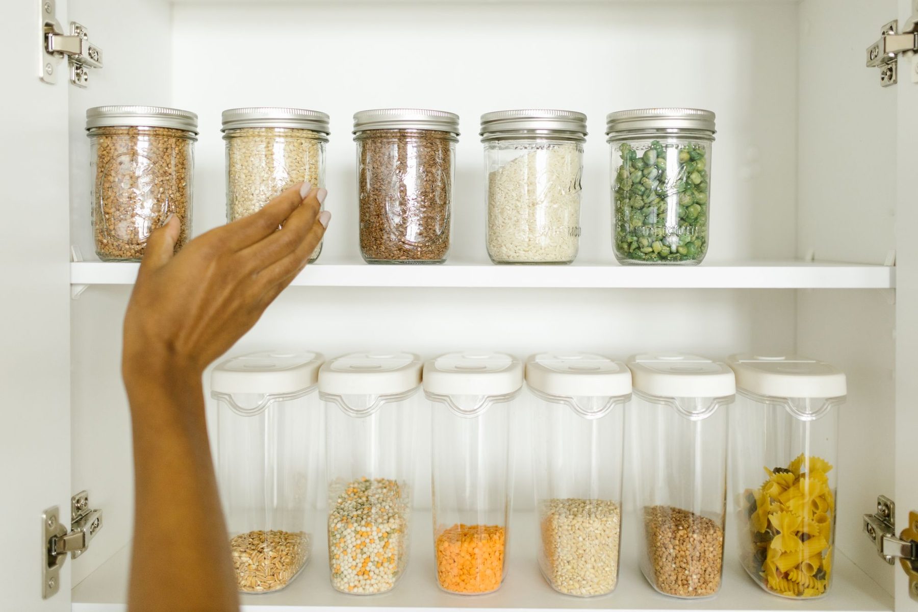 Estantería ordenada con legumbres, cereales y pasta almacenados en botes de vidrio y envases herméticos