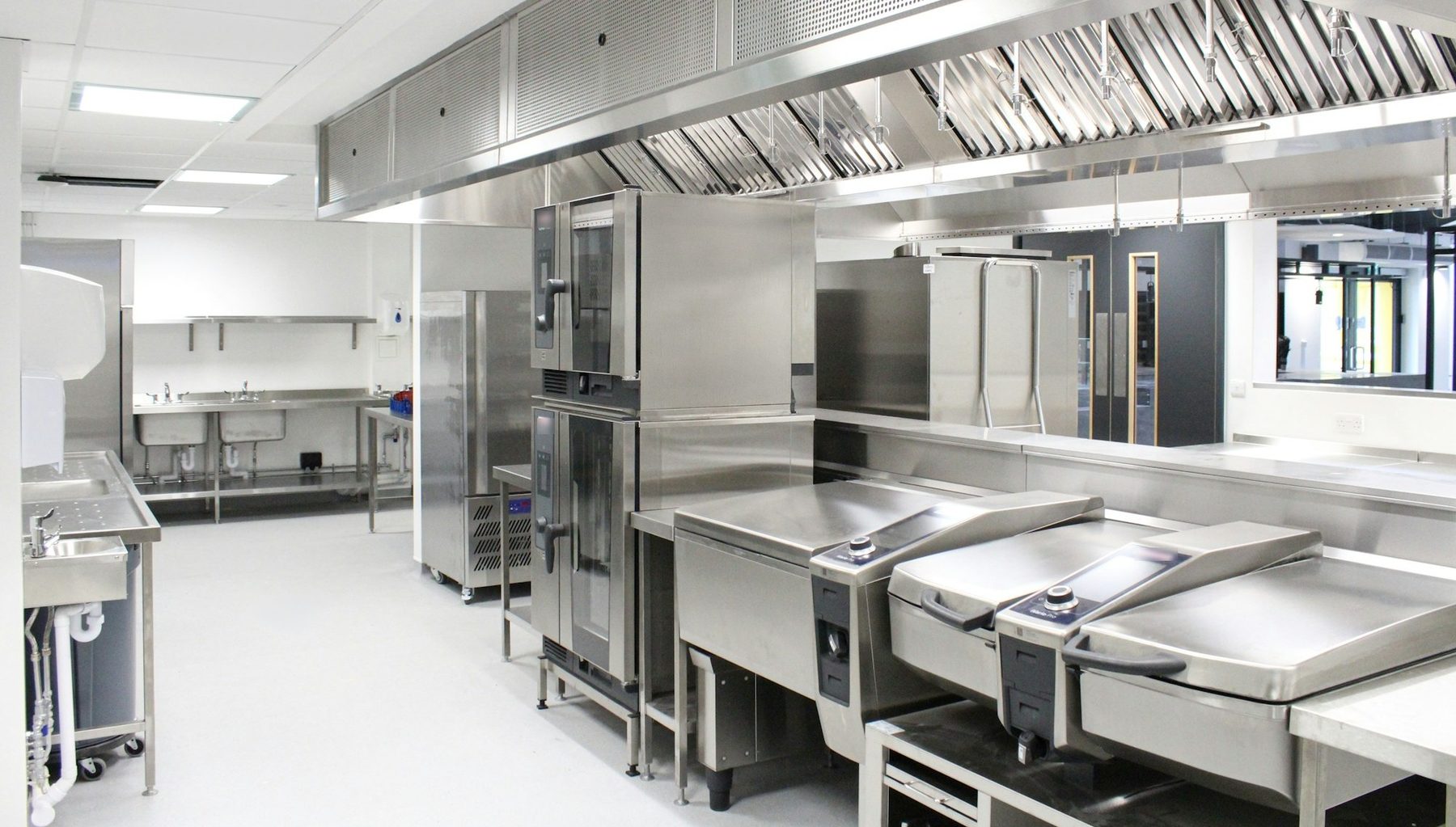 Cocina profesional vacía y muy limpia con campana extractora, hornos y mesas de acero inoxidable