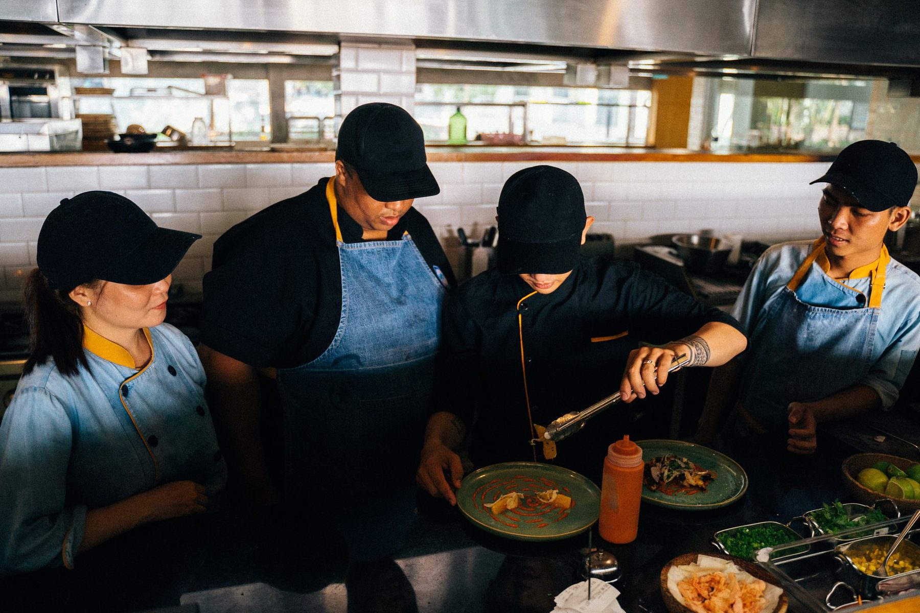 Equipo de cocineros con delantal trabajando juntos en el emplatado de un restaurante