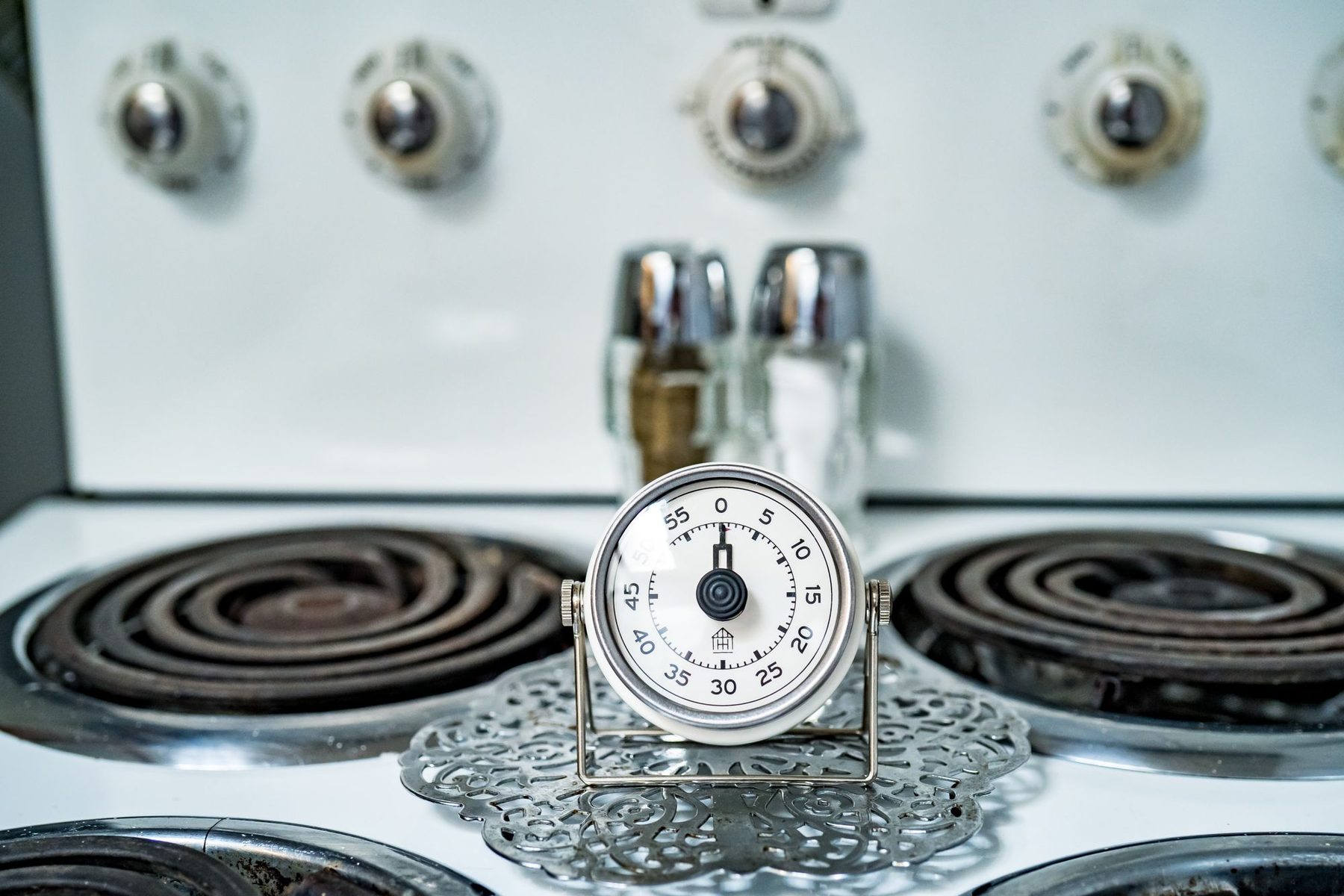 Temporizador analógico de cocina sobre una placa de fuego para controlar el tiempo de cocinado y conservación